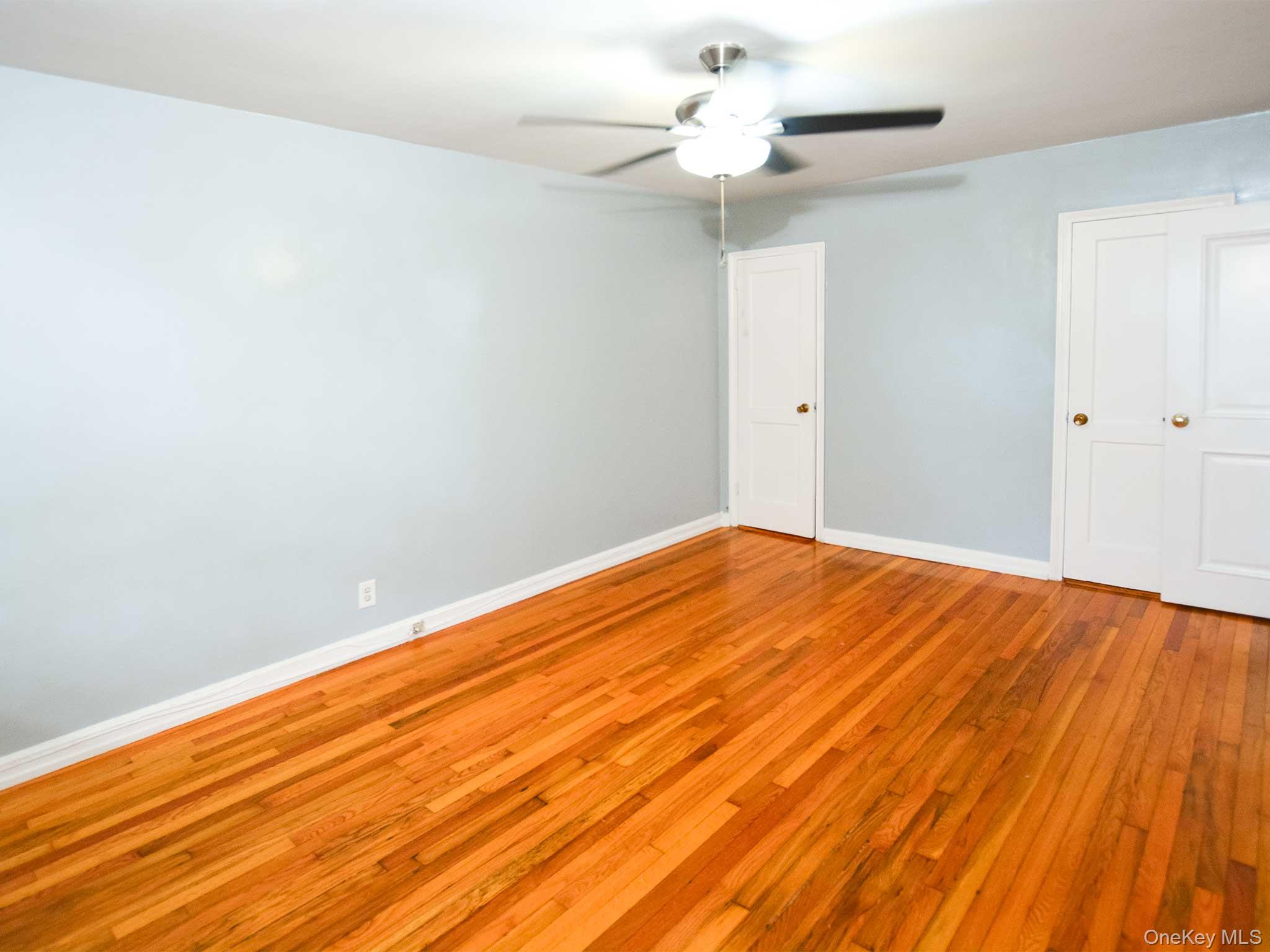 253-27 85th Road, Unit 2 Queens, NY 11426 - Photo 4 of 8 a view of a big room with wooden floor and a ceiling fan