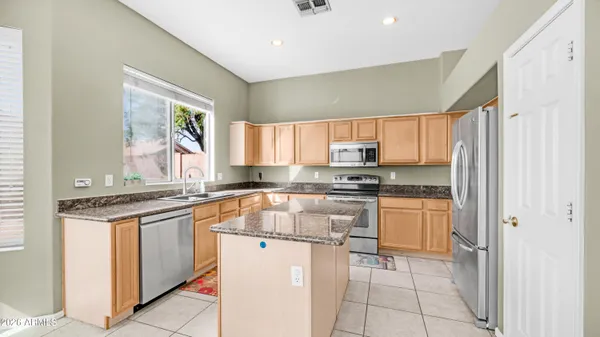 a kitchen with stainless steel appliances granite countertop a sink stove microwave and refrigerator