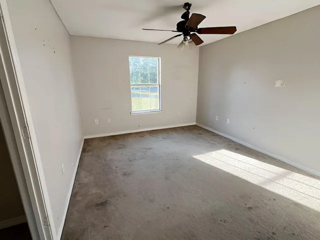 en empty room with windows and a ceiling fan