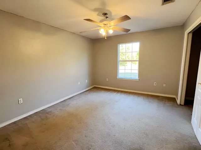 an empty room with windows and fan