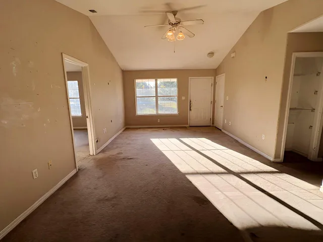 an empty room with windows and fan