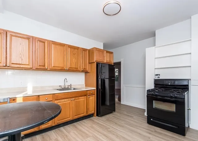 a kitchen with stainless steel appliances granite countertop a stove a refrigerator and a sink with wooden cabinets