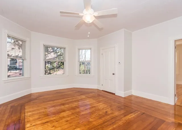 a view of empty room with wooden floor and fan