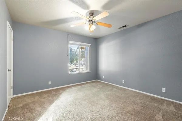 an empty room with windows and fan