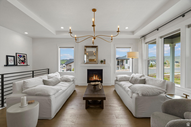 3349 Oxford Loop Morgan, UT 84050 - Photo 11 of 47 Living area featuring hanging lights, a raised ceiling, hardwood / wood-style flooring, and a lit fireplace