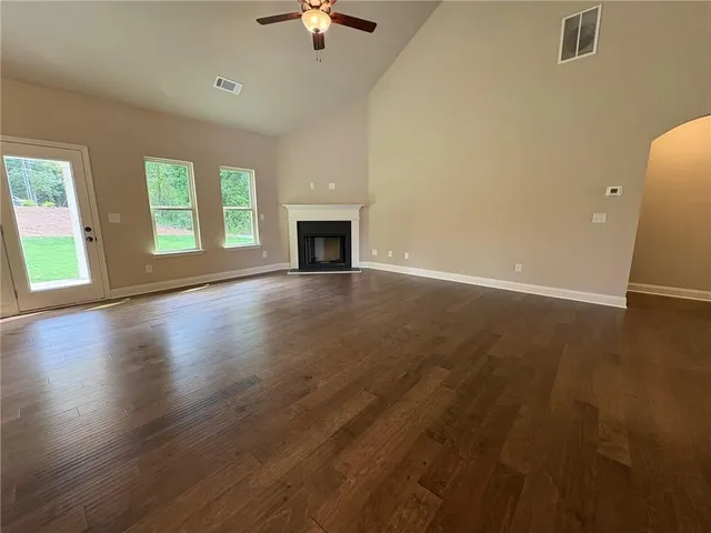 an empty room with wooden floor fireplace and windows
