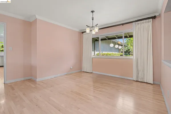 an empty room with wooden floor chandelier and windows