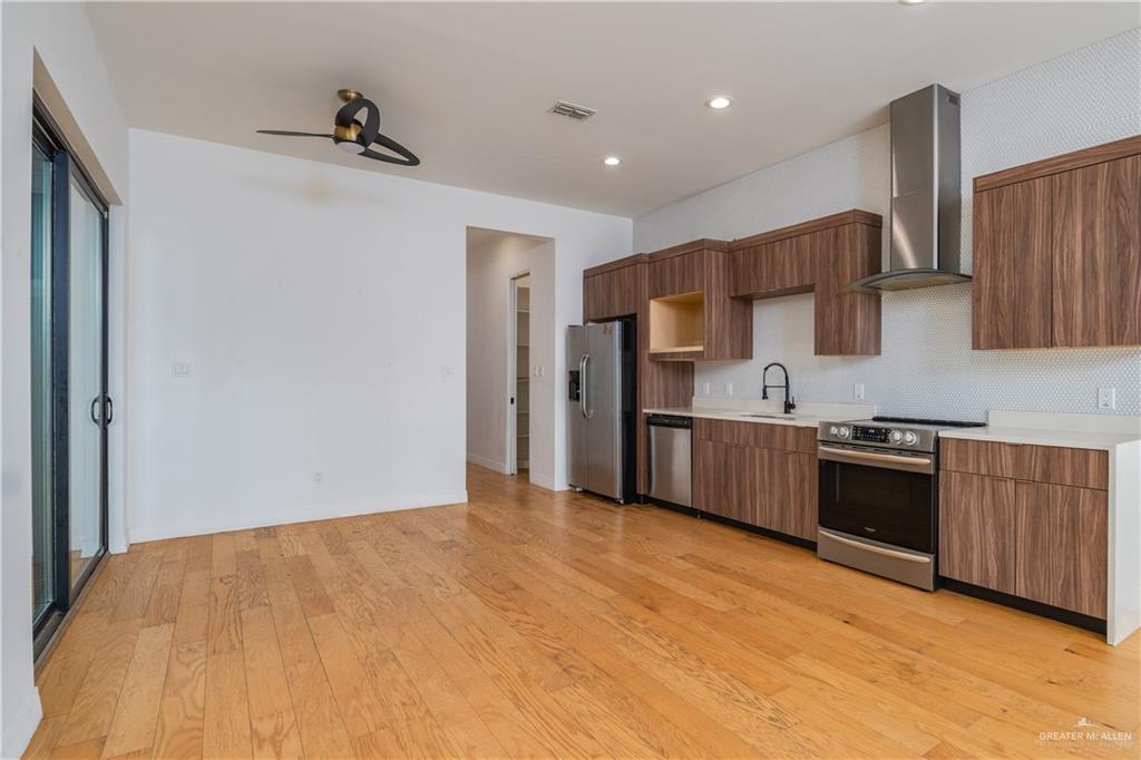 915 Santa Lucia Street Mission, TX 78572 - Photo 5 of 23 Kitchen with stainless steel appliances, wood finish cabinets, light wood-style floors, modern cabinets, and recessed lighting