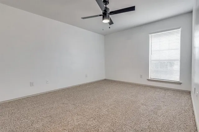 an empty room with a window and a fan