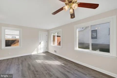 a view of an empty room with chandelier fan and a window