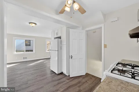 an empty room with wooden floor cabinet and windows