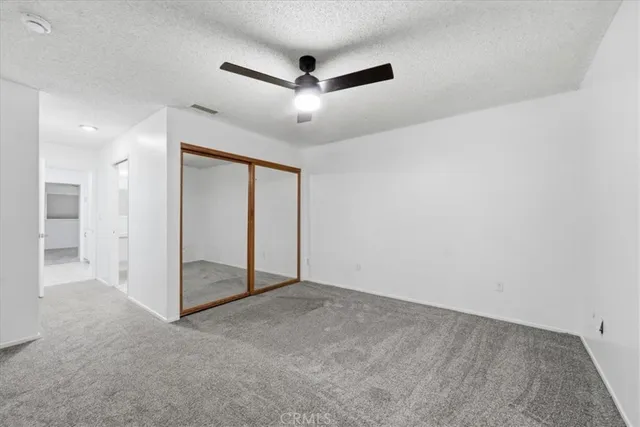 an empty room with closet and a ceiling fan