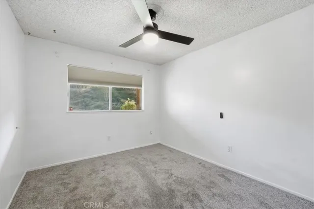 an empty room with a window and a ceiling fan