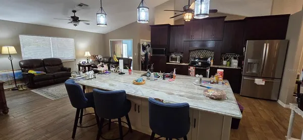 a dining room with stainless steel appliances furniture a chandelier and a kitchen view