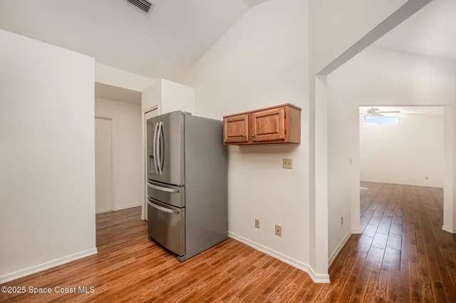a kitchen with a refrigerator and wooden floor