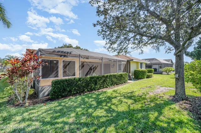 a view of a white house with a big yard and large tree
