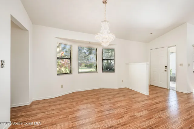 a view of empty room with wooden floor and window