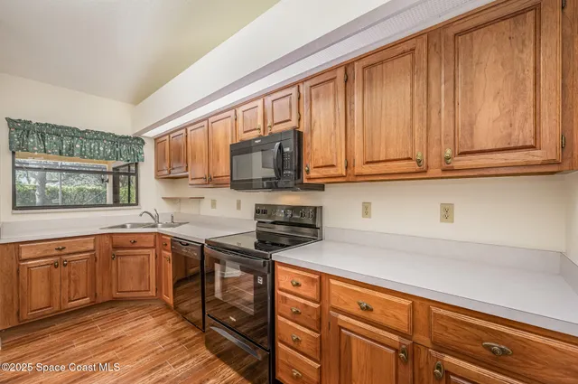 a kitchen with stainless steel appliances granite countertop wooden cabinets a sink and dishwasher a stove top oven with wooden floor