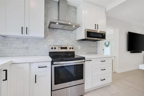 a kitchen with stainless steel appliances a sink a stove a refrigerator cabinets and living room view