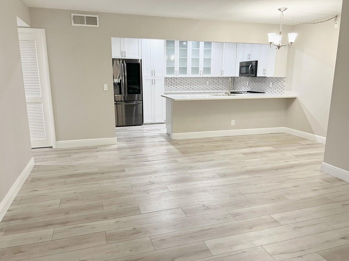 a view of kitchen with granite countertop cabinets and refrigerator