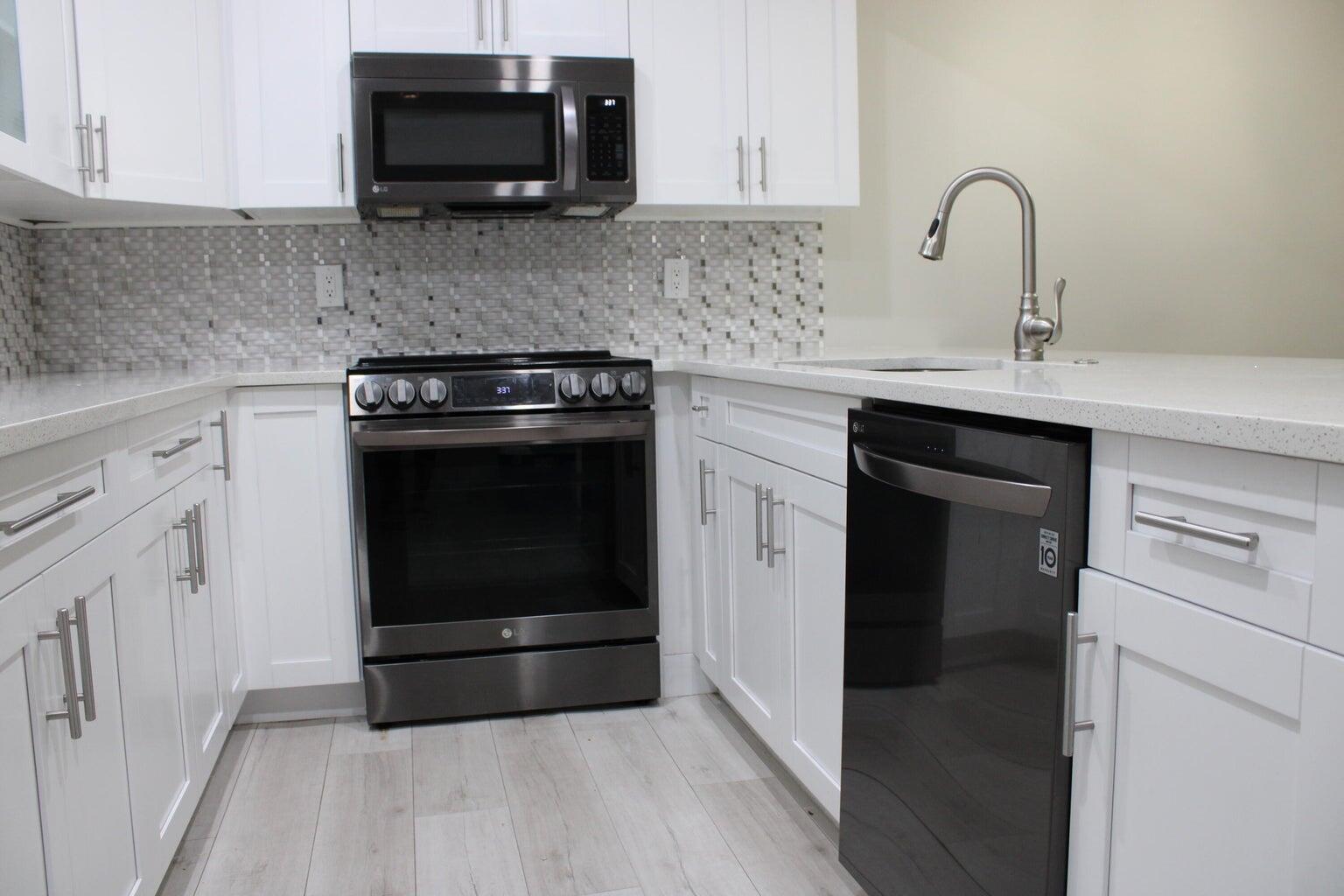 1006 Green Pine Boulevard, Unit A1 West Palm Beach, FL 33409 - Photo 4 of 25 a kitchen with granite countertop a stove and a sink