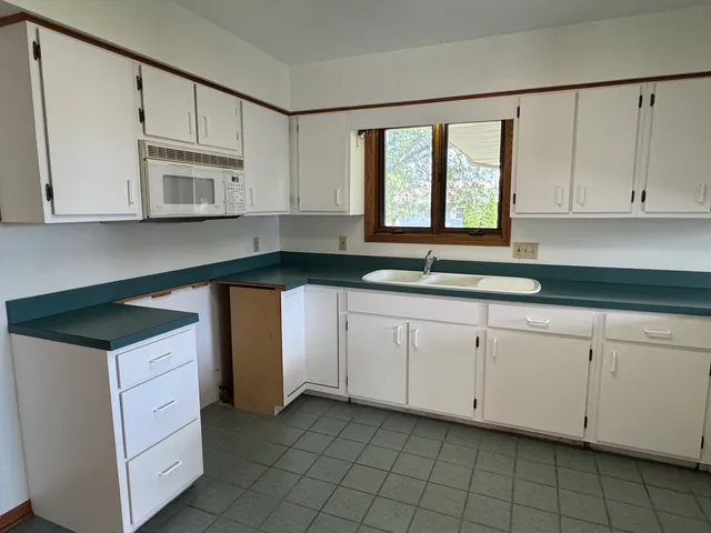 a kitchen with granite countertop white cabinets and white appliances