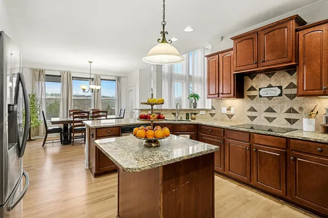 a kitchen with granite countertop a stove a sink dishwasher a dining table and chairs with wooden floor