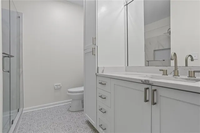 a bathroom with a granite countertop toilet a sink and a mirror