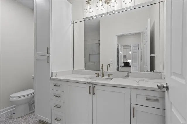a bathroom with a granite countertop sink a toilet and a mirror