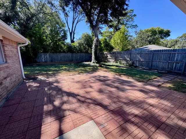 a view of a backyard with large trees and wooden fence