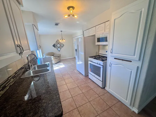 a kitchen with granite countertop a stove a sink and a refrigerator