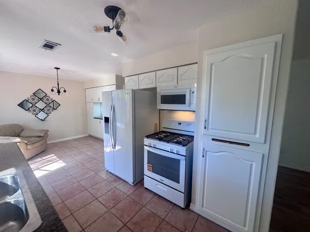 a kitchen with stainless steel appliances granite countertop a refrigerator a stove and a sink