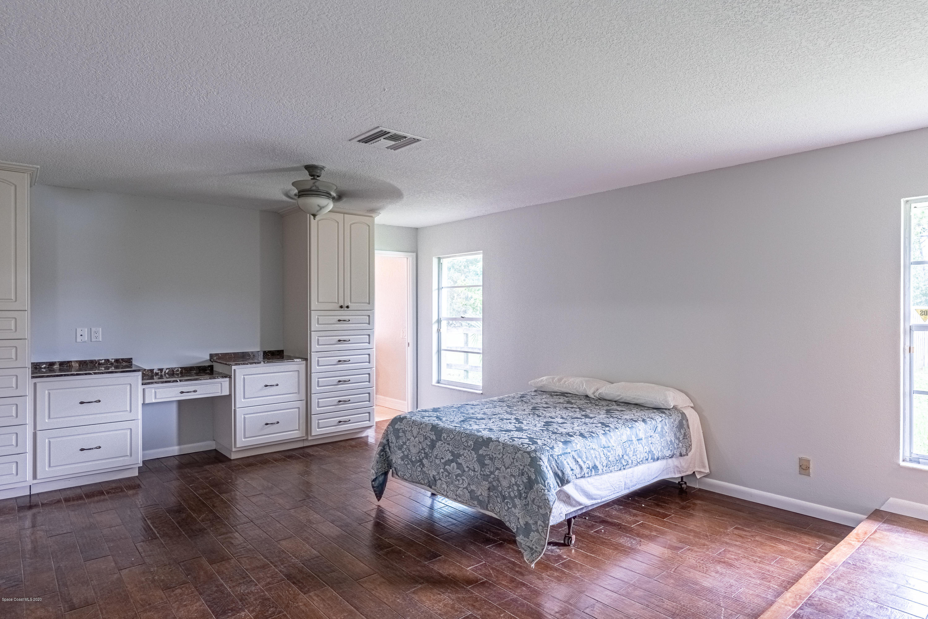 4300 Pinewood Road Melbourne, FL 32934 - Photo 23 of 60 a spacious bedroom with a bed and cabinets