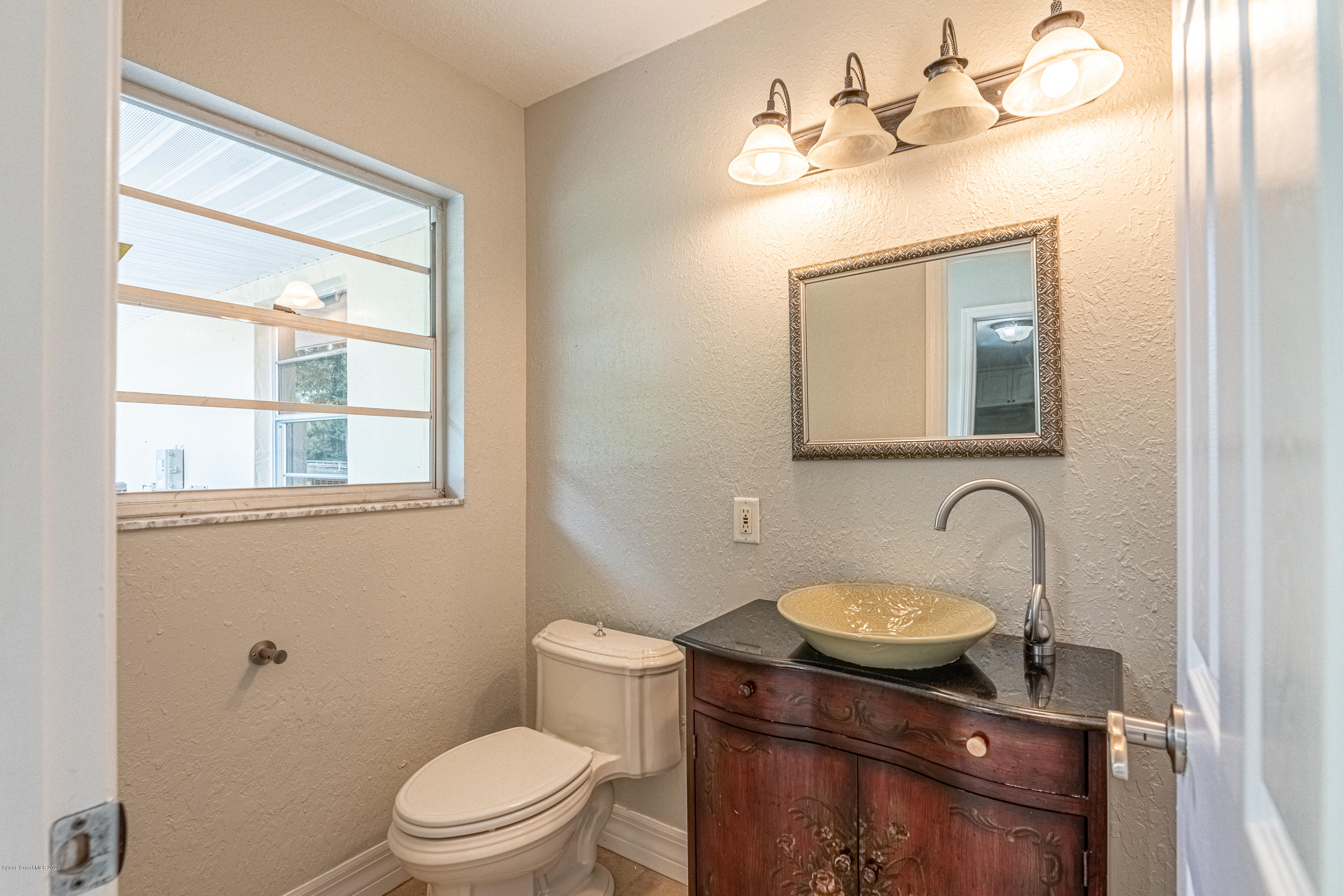 4300 Pinewood Road Melbourne, FL 32934 - Photo 40 of 60 a bathroom with a toilet a sink a mirror a window and vanity