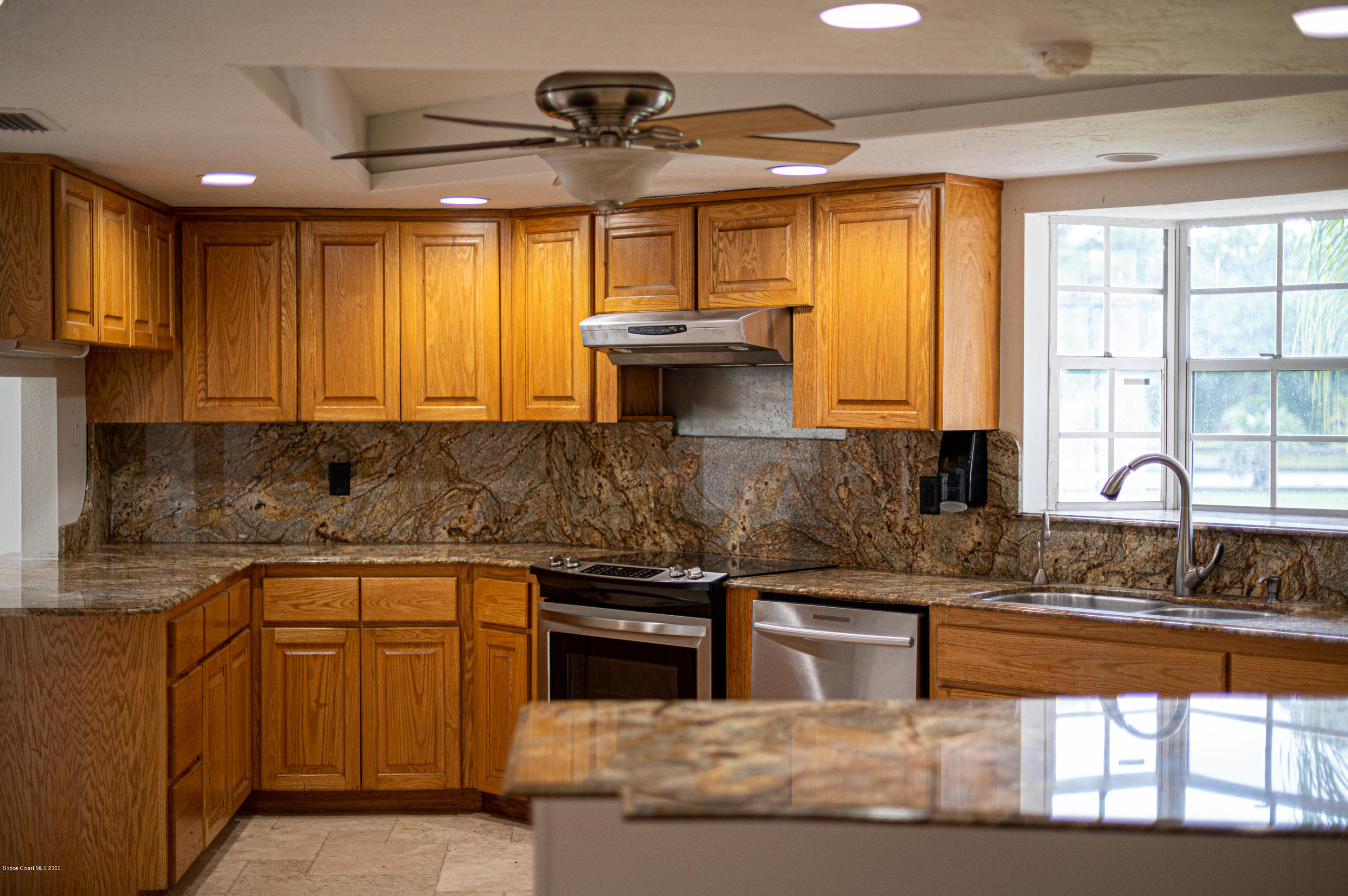4300 Pinewood Road Melbourne, FL 32934 - Photo 43 of 60 a kitchen with stainless steel appliances granite countertop a sink a stove cabinets counter space and a window