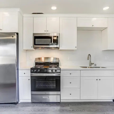 a kitchen with stainless steel appliances white cabinets and a stove a refrigerator with a sink