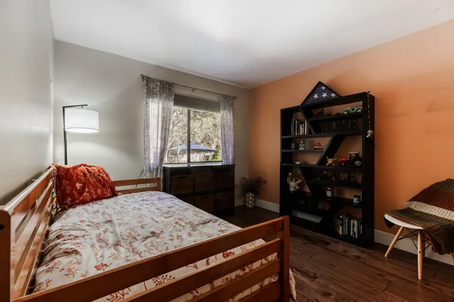 a bedroom with a bed and a dresser with wooden floor