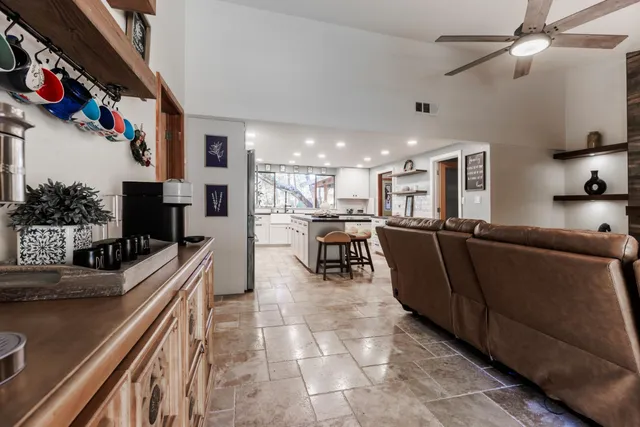 a living room with couches a flat screen tv and kitchen view