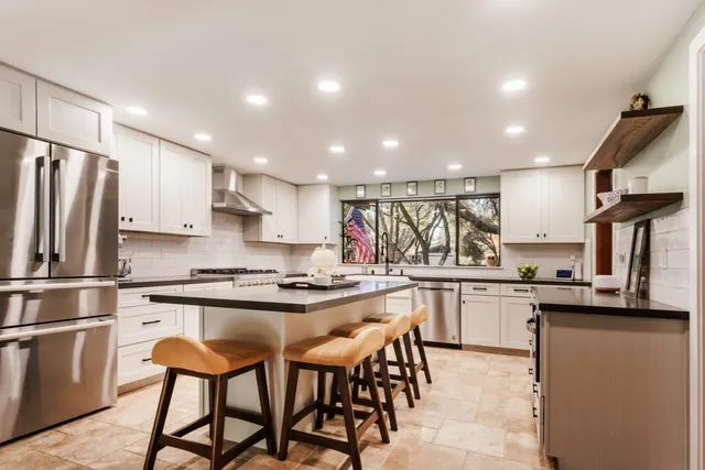 a kitchen with stainless steel appliances kitchen island granite countertop a table and chairs in it