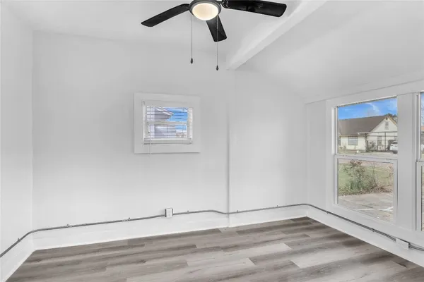 an empty room with windows and fan