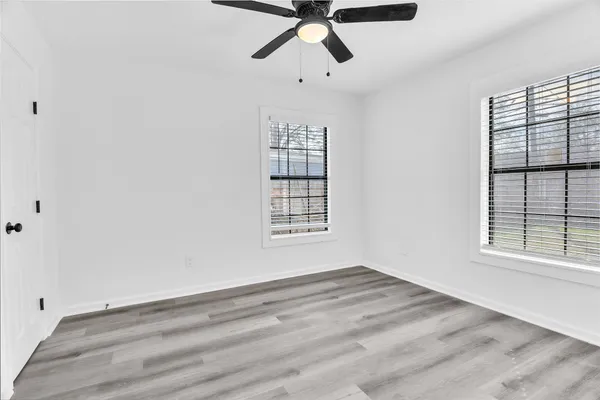 a view of empty room with wooden floor and fan
