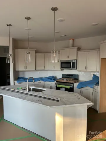 a kitchen with stainless steel appliances granite countertop a sink a stove a refrigerator white cabinets and countertops with wooden floor