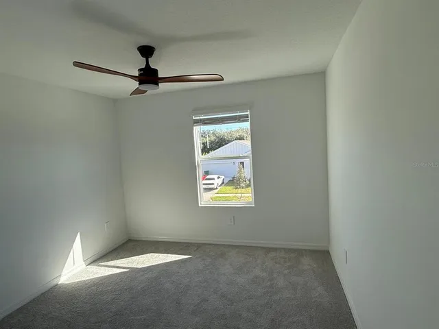 an empty room with windows and fan