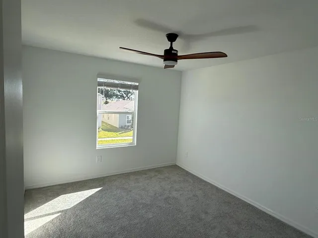 an empty room with a window and a fan