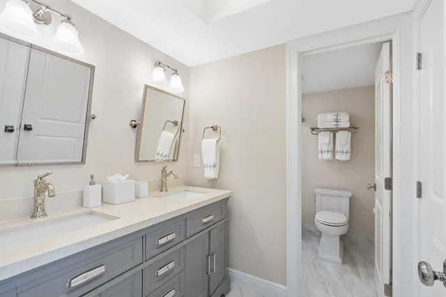 a bathroom with a granite countertop sink a toilet and a mirror