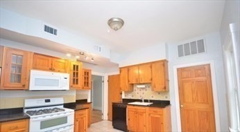 341 Summer Street, Unit 2F Somerville, MA 02144 - Photo 4 of 17 a kitchen with granite countertop a stove and a refrigerator