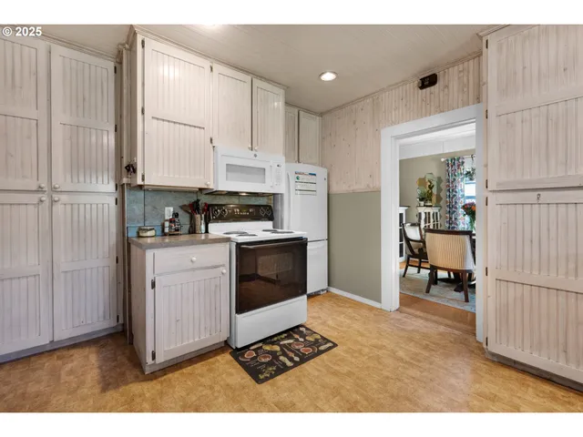 a kitchen with stainless steel appliances kitchen island granite countertop a refrigerator oven a sink with white cabinets and wooden floor