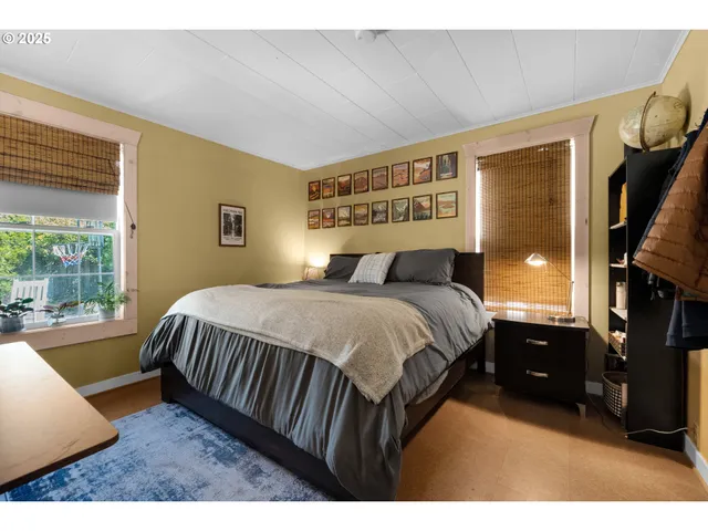 a bedroom with a bed a dresser and a large window