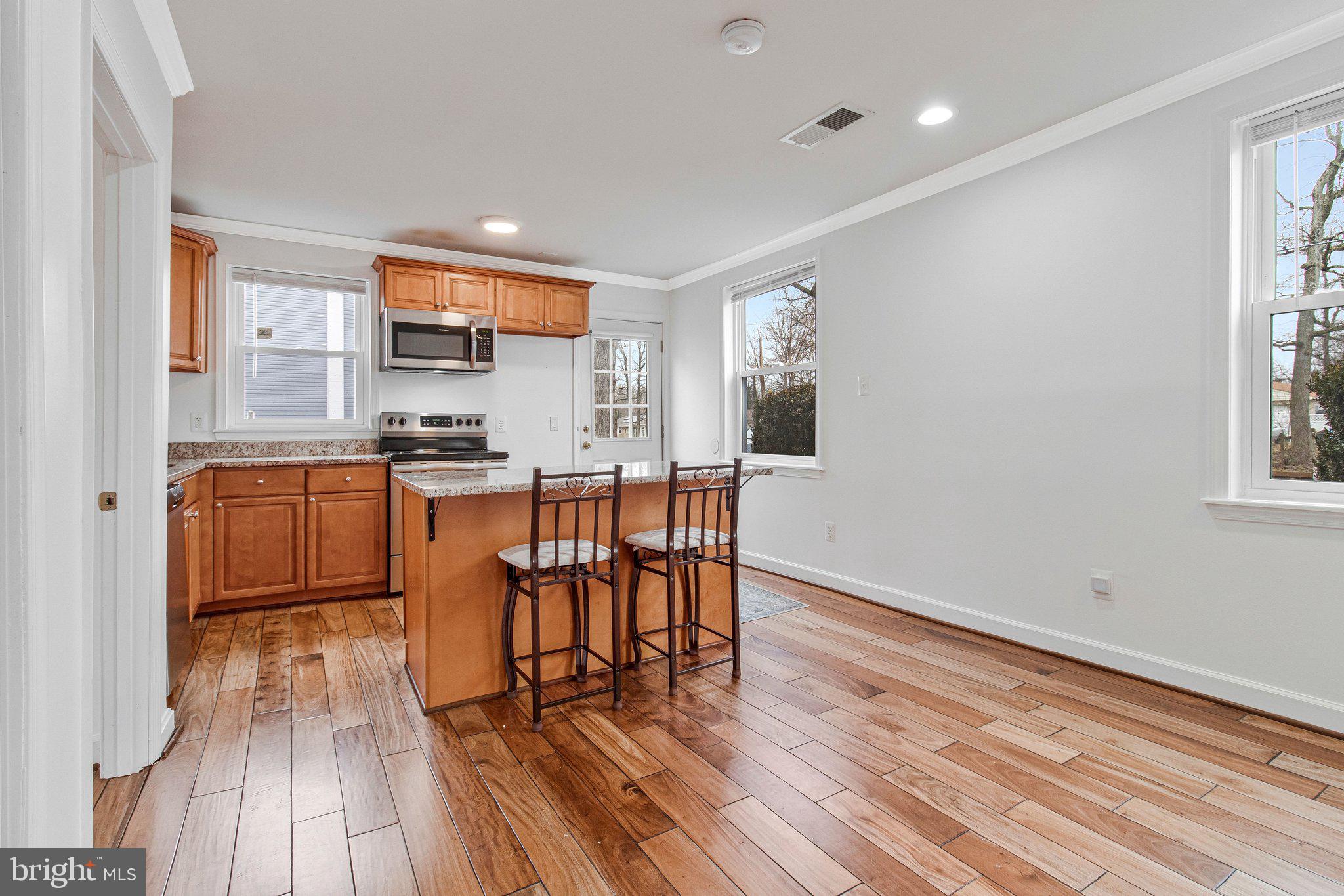 8600 Lantern Lane Clinton, MD 20735 - Photo 13 of 40 a kitchen with stainless steel appliances granite countertop a stove top oven a sink dishwasher and a dining table with wooden floor