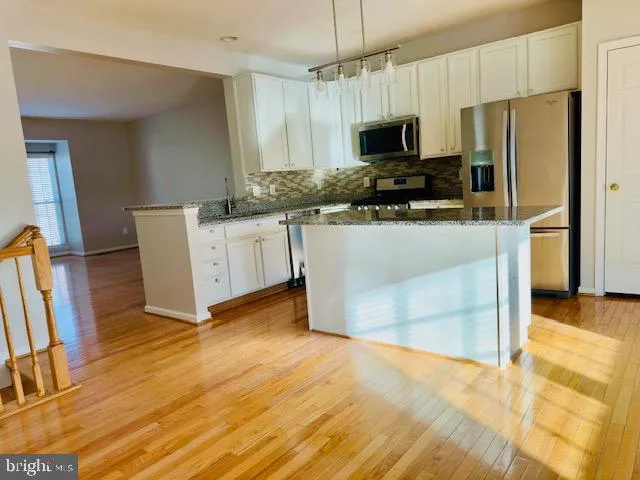 a kitchen with granite countertop a refrigerator and a stove top oven